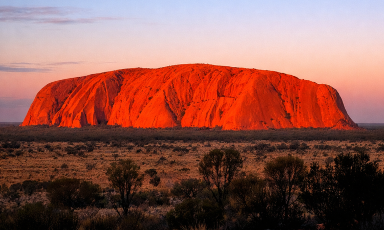 Uluru glowing orange at sunrise viewed from Talinguru Nyakunytjaku platform in Red Centre