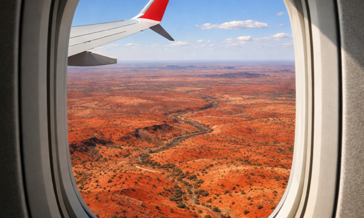 Aerial view of Australian Outback from plane window showing vast red desert landscape