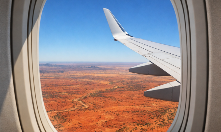Aerial view of red Australian outback from airplane window while flying between cities