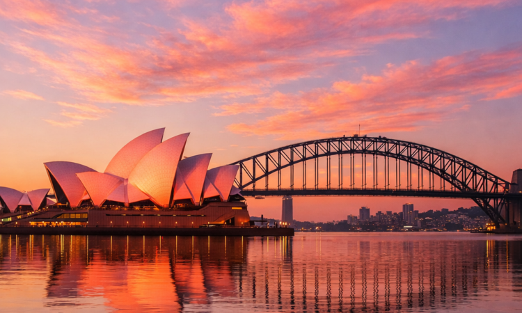 Sydney Opera House at sunrise with pink-tinted sails reflected in calm harbour waters
